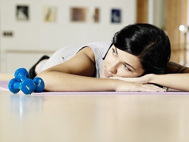 Una mujer, cansada tras hacer ejercicio en el gimnasio./GTRES