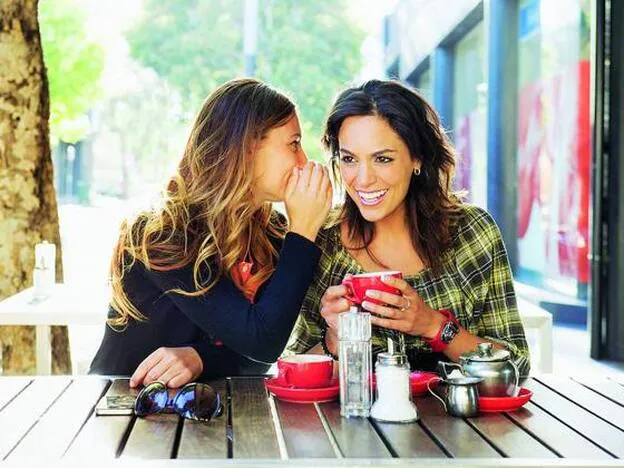 Dos mujeres comparten confidencias mientras toman un café./GETTY