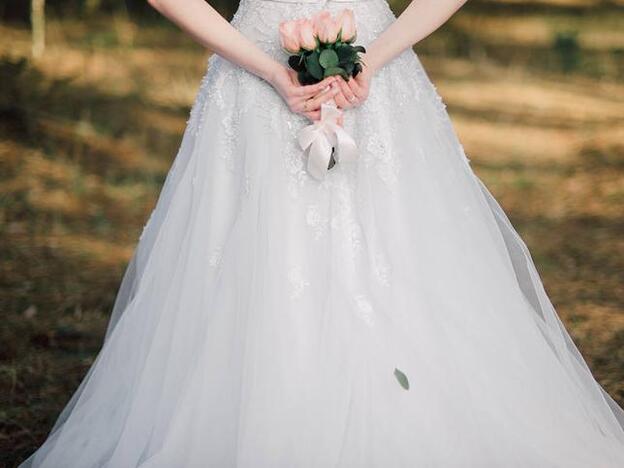 Una mujer el día de su boda sujetamdo un ramo de flores./fotolia