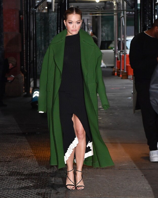 Rita Ora acudió al programa 'Next Top Model' de Tyra Banks con un vestido negro 'tail hem' con vivos en blanco, un abrigo verde de Emilio Pucci.