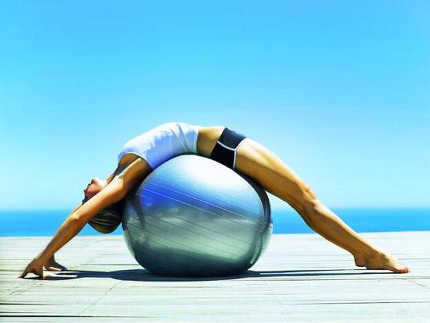 Una mujer, practicando ejercicio con una fitball./GETTY