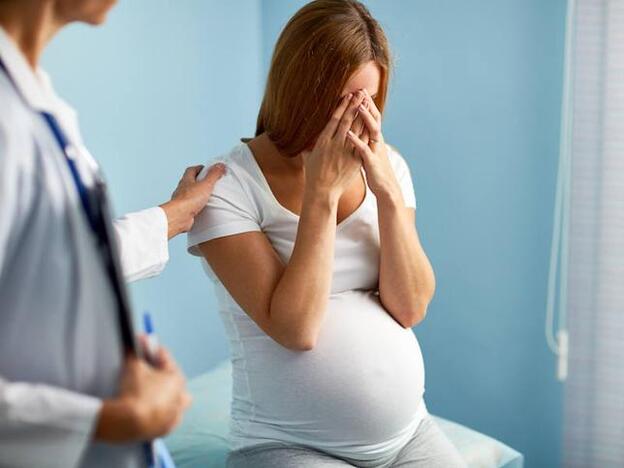 Una mujer embarazada, angustiada en la consulta./fotolia