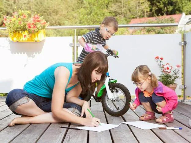Una madre, dibujando con sus hijos en la terraza./GTRES