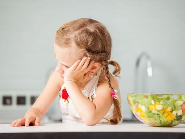 Niña negándose a comer una ensalada/Fotolia