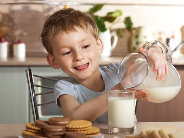 Un niño llenando un vaso de leche./adobe stock