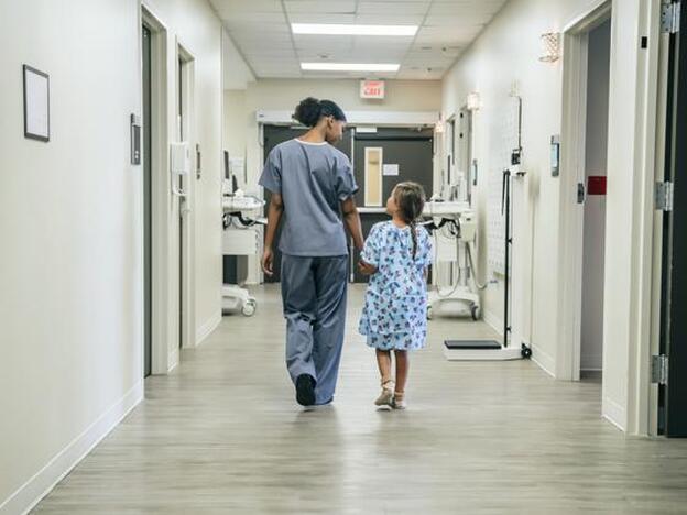 Una enfermera y una niña caminando por el hospital./getty