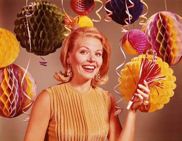 UNITED STATES - CIRCA 1960s:  Blonde woman smiling surrounded by confetti, balloons and party decorations./
