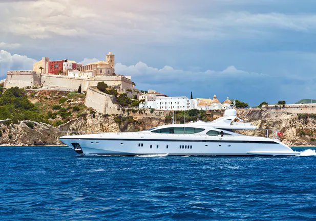 Waterside view of the Dalt Vila of Ibiza and motor yacht. The fortification of the city were listed as a UNESCO Heritage Site in 1999. Balearic Islands, Spain/