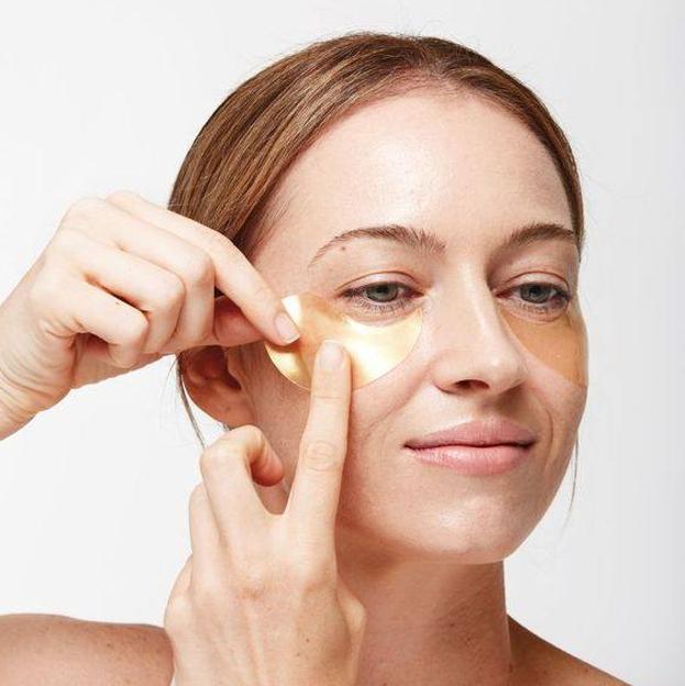 Mujer aplicando parches de ojos en el rostro