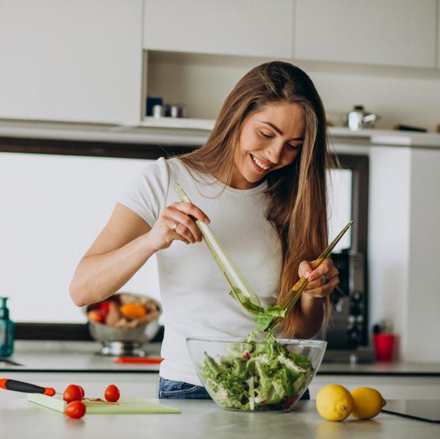 Mujer en una cocina haciendo una ensalada. 