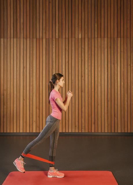 Mujer entrenando piernas con banda de resistencia/PEXELS