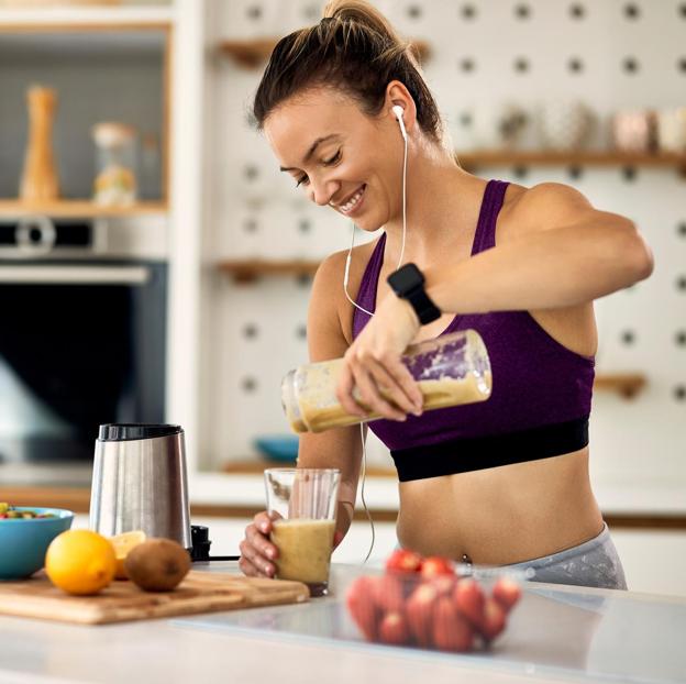 Mujer joven cocinando después de su entrenamiento. 