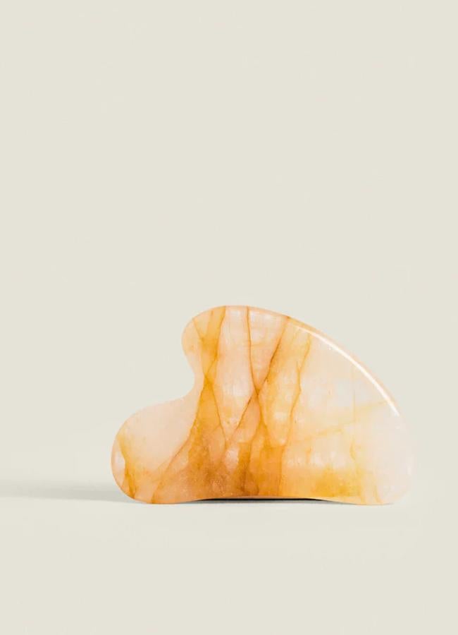 Masajeador facial Gua Sha en cuarzo amarillo.