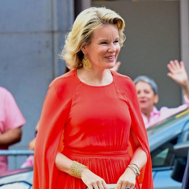 Matilde de Bélgica con un vestido capa de color rojo.