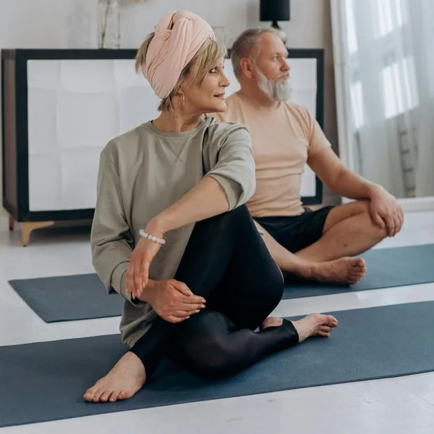 Mujer haciendo yoga junto a su marido. 