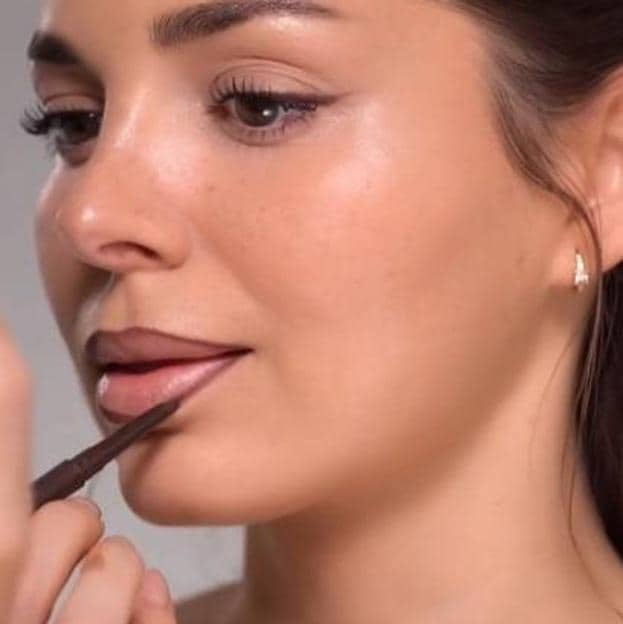 Maquilladora perfilando los labios con lápiz marrón