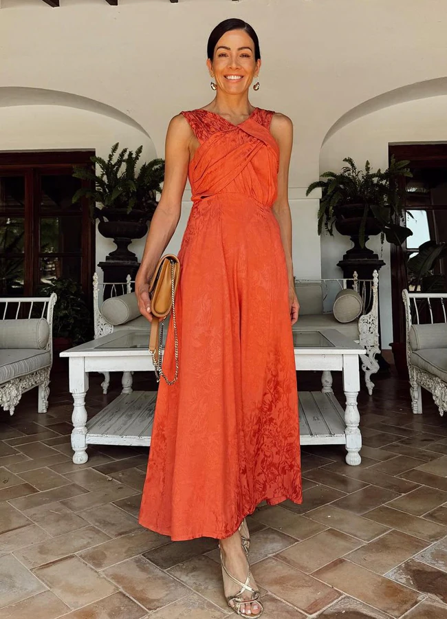 Virginia Troconis, con un look de invitada perfecto de vestido naranja y sandalias doradas. INSTAGRAM @VIRTROCONIS