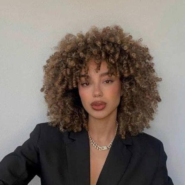 Influencer con corte de pelo rizado afro tendencia para otoño