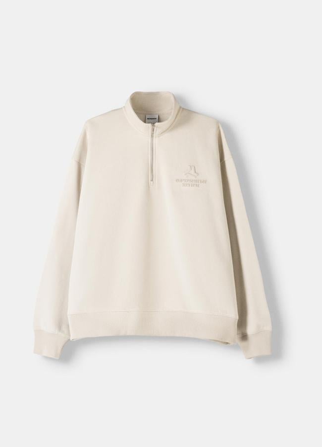 Sudadera beige con cuello subido y cremallera lateral de Bershka, 19,59 euros.