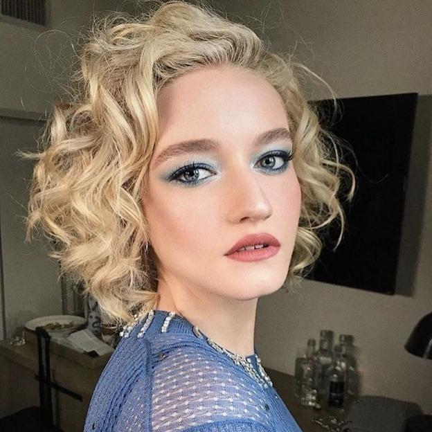 Julia Garner con corte de pelo rizado estilo stacked bob